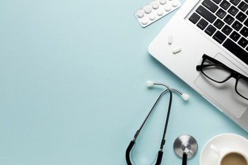 Medical tools with notepad; laptop and cup of coffee over desk