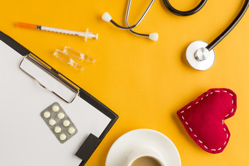 Medicines over clipboard with stitched heart; ampoule; stethoscope and coffee cup; injection on...