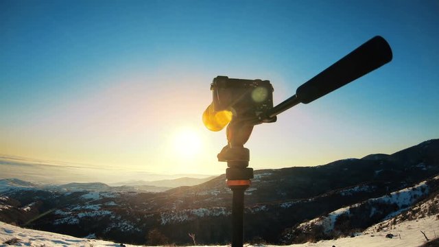 Photographer uses camera and tripod to capture a beautiful landscape picture at twilight. Winter scenery with snow-covered mountains