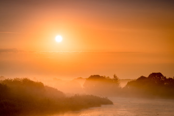 Misty orange sunrise over the lake. Seasonal autumn colors