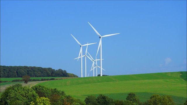 Windkraftanlage mit vielen Windr&auml;dern gestaffelt vor blauem Himmel &ndash; Wind turbine with many windmills staggered in front of blue sky