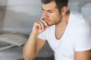 handsome businessman in white t-shirt thinking on the grey sofa in living room with free copy space for your text