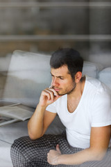 handsome businessman in white t-shirt thinking on the grey sofa in living room with free copy space for your text