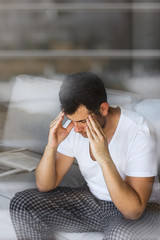 handsome businessman in white t-shirt thinking on the grey sofa in living room with free copy space for your text