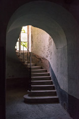 Un escalier montant sous une arche. Un ancien escalier et une arche.