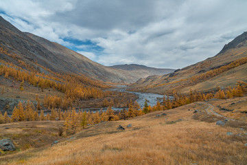 Naklejka premium Winding river on a background of mountains and autumn trees