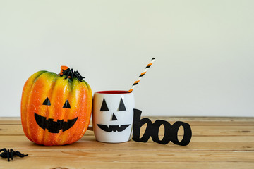 Accessories of decorations Happy Halloween day background concept.Jack O Lanterns cup of drink with boo text and pumpkins of object to party season on modern rustic brown & white stone backdrop.