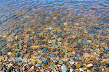 Colored stones on the seashore under water. Landscape for design.