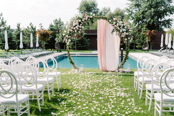 A stylish round green arch for a wedding ceremony on the lawn near the pool.