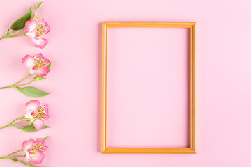 Greeting card concept. Alstroemeria flowers and wooden frame on a pink pastel background. Top view composition with copy space