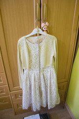 A white short dress with a jacket hangs on a hanger.