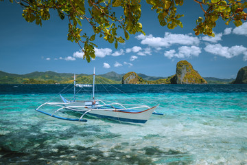 Palawan, Philippines. Island hopping trip in El Nido. Incredible dreamlike exotic scenery with traditional filippino banca boat moored in turquoise ocean water