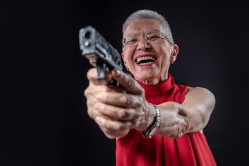 Fototapeta na wymiar Old lady aiming with her weapon while smiling