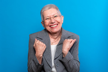 Satisfied old business lady, feeling happy, fists gesture