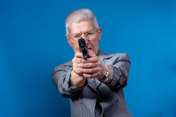 Old business lady aiming with her weapon, looking angry