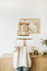 Young pretty woman hold Christmas / New Year gift boxes with bows. Traditional winter holidays gifts packaging creative concept. Flat lay, top view.