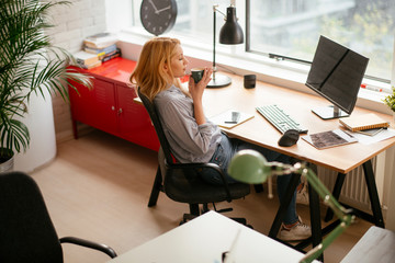 Young businesswoman drinking coffee in her office