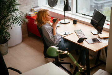 Young businesswoman drinking coffee in her office