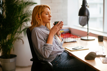 Young businesswoman drinking coffee in her office