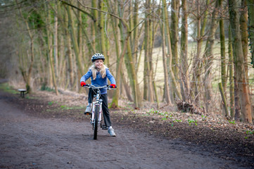 Fototapeta premium Smiling, happy young blonde girl paused on her bike on a country path