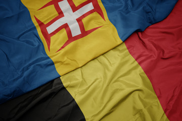 waving colorful flag of belgium and national flag of madeira.