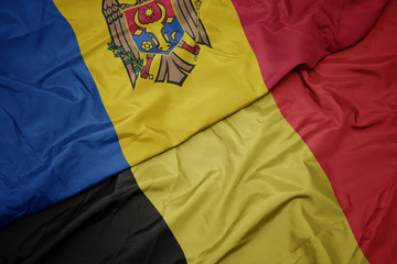 waving colorful flag of belgium and national flag of moldova.
