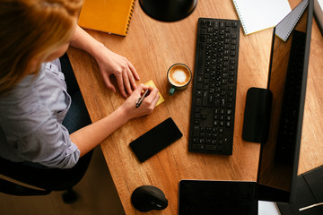 Close up of woman taking notes on sticker paper