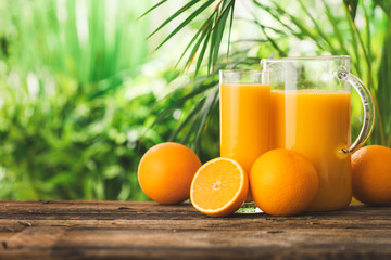 Glass and jug of fresh orange juice on table outdoors