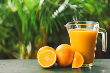 Jug of fresh orange juice on table outdoors