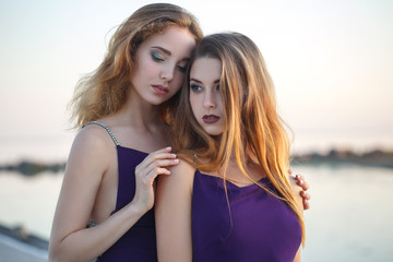 Fototapeta na wymiar Two beautiful girls in identical dresses on the seashore.