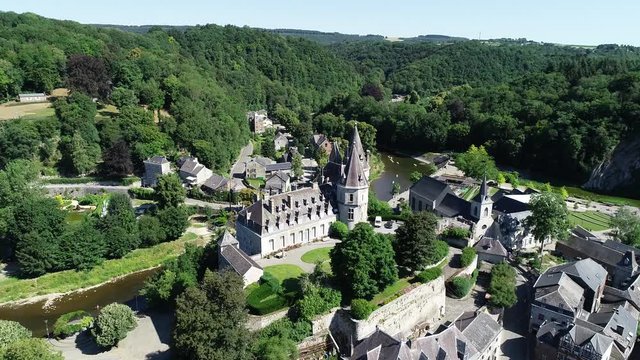 Aerial 4K, drone flying around old town and Castle in Durbuy, Belgium, surrounded by mountains, river and kayakers on the river in green kayaks paddling in a beautiful green scenery in summertime