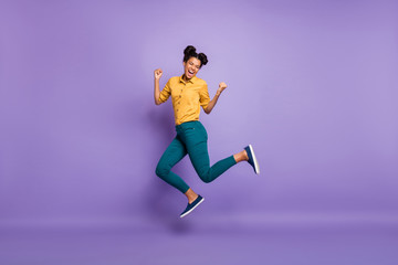 Full length profile photo of pretty dark skin lady jumping high celebrating favorite team victory wear casual yellow shirt trousers isolated purple color background