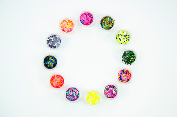 Top view round circle shaped acrylic jars with multicolored glitters for nails on a white background. Spangles for nails mockup with copy space
