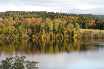 Autumn landscape of mountain and lake, with the colorful trees, symmetric reflection in the clean water