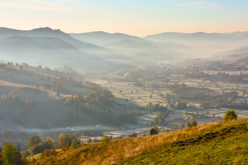 Beautiful landscape mountain hill meadow sunrise foggy morning village Bucovina Romania 