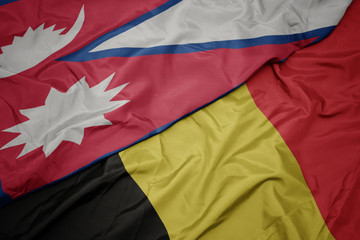 waving colorful flag of belgium and national flag of nepal.