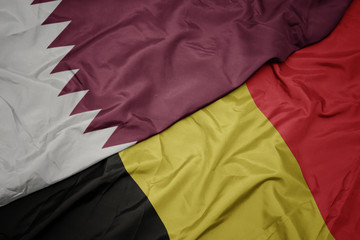 waving colorful flag of belgium and national flag of qatar.