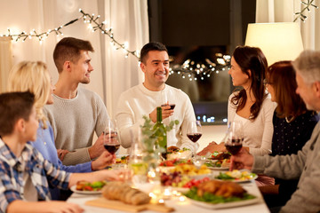 celebration, holidays and people concept - happy family having dinner party, drinking red wine and toasting at home