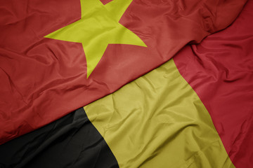 waving colorful flag of belgium and national flag of vietnam.