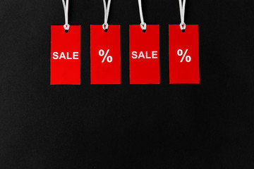 shopping, sale and outlet concept - red tags with discount signs on black background