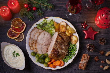 Roasted sliced ham on white plate, table with Christmas decorations. Dish for Christmas Eve. Winter season holidays food. Overhead, flat lay
