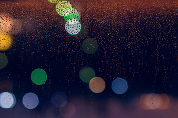 Rain drop on glass window in monsoon season with colorful bokeh lights for abstract and background...
