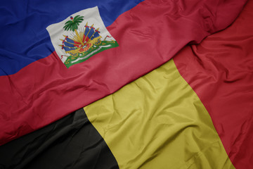 waving colorful flag of belgium and national flag of haiti.