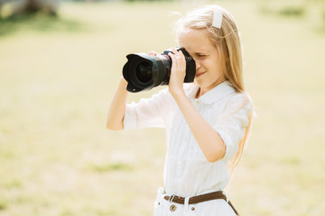 young girl takes camera outdoors , child with a camera