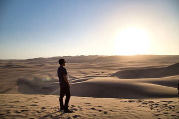 Fototapeta na wymiar young man on sand in a desert near Huacachina, Ica region, Peru. The sunset desert viewyoung man on sand in a desert near Huacachina, Ica region, Peru. The sunset desert view