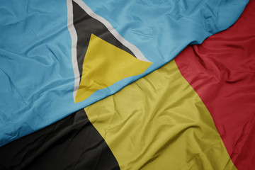 waving colorful flag of belgium and national flag of saint lucia.