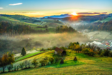 Beautiful scenery landscape Romania village mountains hills fields foggy morning first ray splitting light