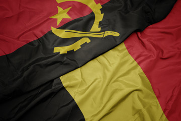 waving colorful flag of belgium and national flag of angola.