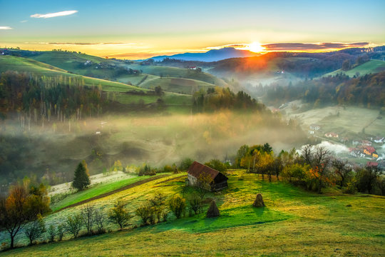 Beautiful scenery landscape Romania village mountains hills fields foggy morning first ray splitting light © Cristi