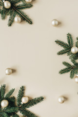 Christmas / New Year holiday composition. Mock up frame with blank copy space, fir needle branches, Christmas baubles on beige background. Flat lay, top view festive concept.